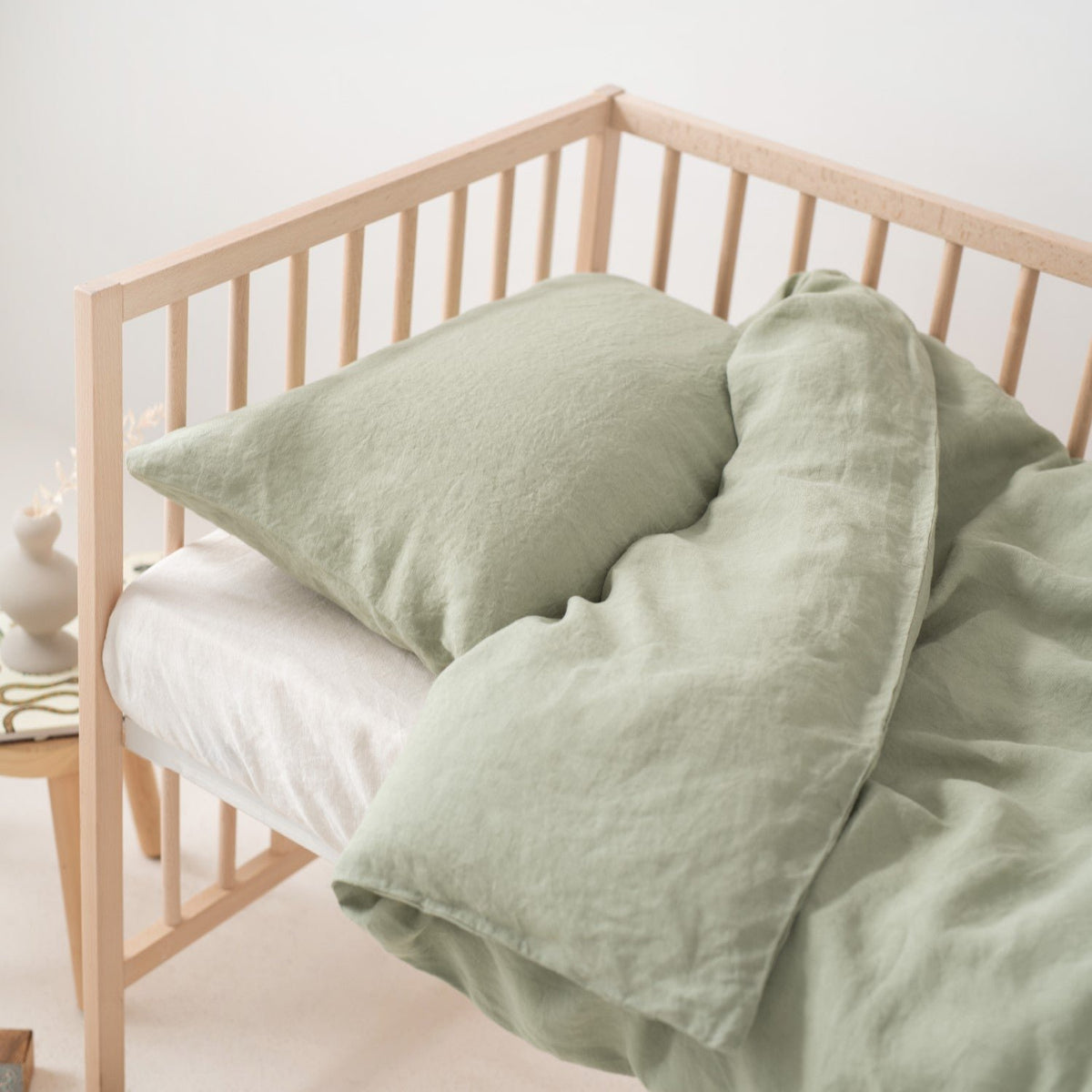 9. Close-up of crib with sage green linen duvet cover and pillowcase
