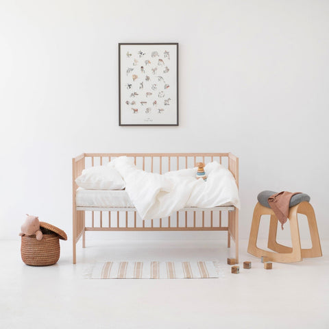 1. Kids' room with white linen duvet cover set on a wooden crib, surrounded by toys and decor