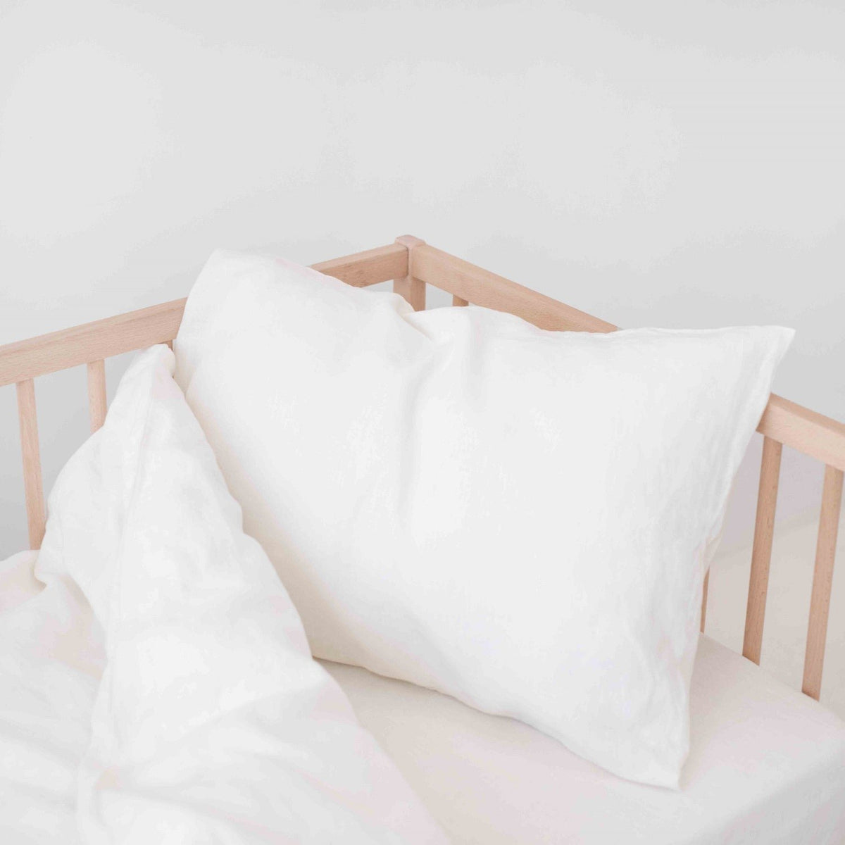 2. White linen pillow and duvet cover on a crib, highlighting fabric softness