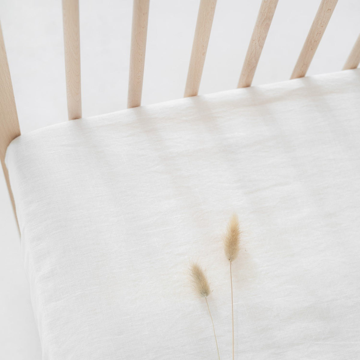 2. Close-up of white linen fitted sheet on crib, highlighting the fabric texture and natural fibers