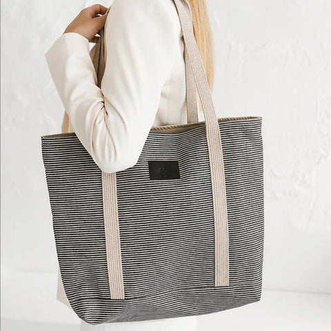 1. Woman holding Muni striped denim tote bag in lifestyle setting