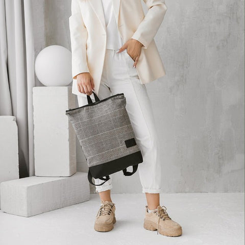 2. Woman holding MUNI Tartan Backpack, highlighting versatile style and urban appeal