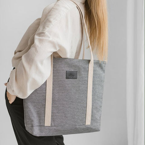 3. Woman wearing Muni striped denim tote bag over shoulder in studio
