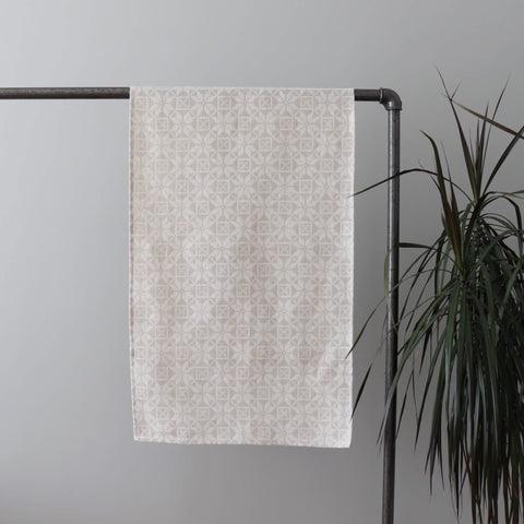2. Beige table runner with kaheksakanna pattern hanging on metal rack, indoor plant beside
