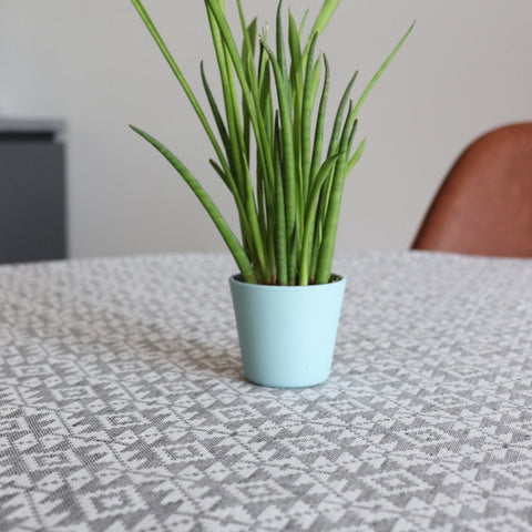 2. Close-up of LOKO Harjumaa tablecloth with traditional mitten pattern, featuring a green plant in a blue pot on top