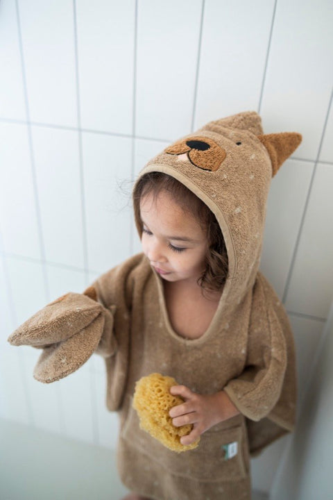 1. Child wearing Trixie Baby Mr. Dog hooded poncho in bathroom, holding sponge, playful dog design on hood
