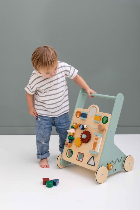 1. Child playing with Trixie Baby Wooden Activity Walker featuring colorful shapes and animal designs indoors