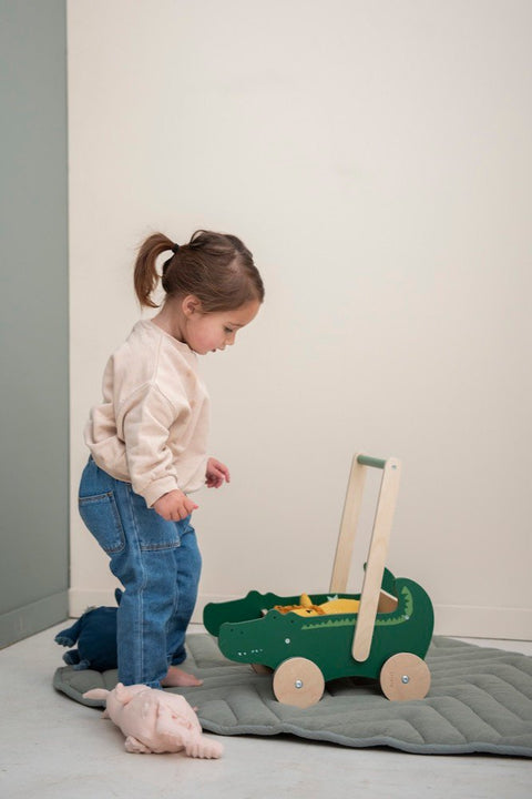 3. Child playing with Trixie Baby Wooden Cart featuring crocodile design, in a cozy indoor setting