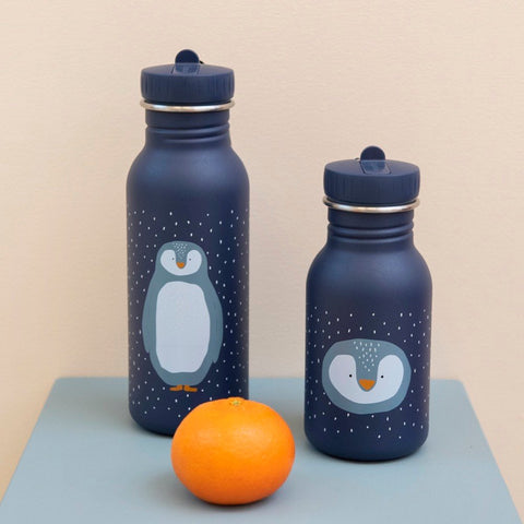 1. Two Trixie Baby stainless steel bottles with penguin design on blue background, one larger and one smaller, with an orange in front