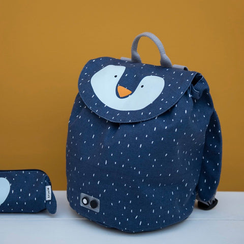 1. Trixie Baby Mini Drawstring Backpack in navy with Mr Penguin design, displayed on a white surface against a mustard background