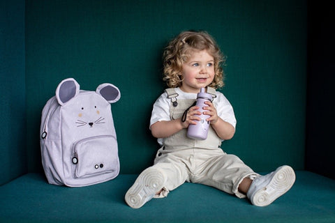 1. Child sitting with Trixie Baby Mrs Mouse backpack in a cozy setting, holding a matching water bottle