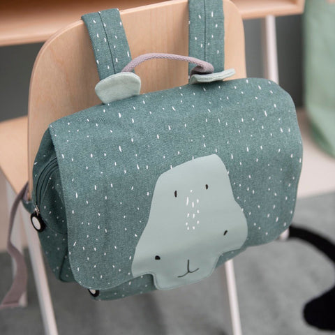 1. Trixie Baby Mr Hippo school bag hanging on a chair, showcasing playful hippo design and adjustable straps