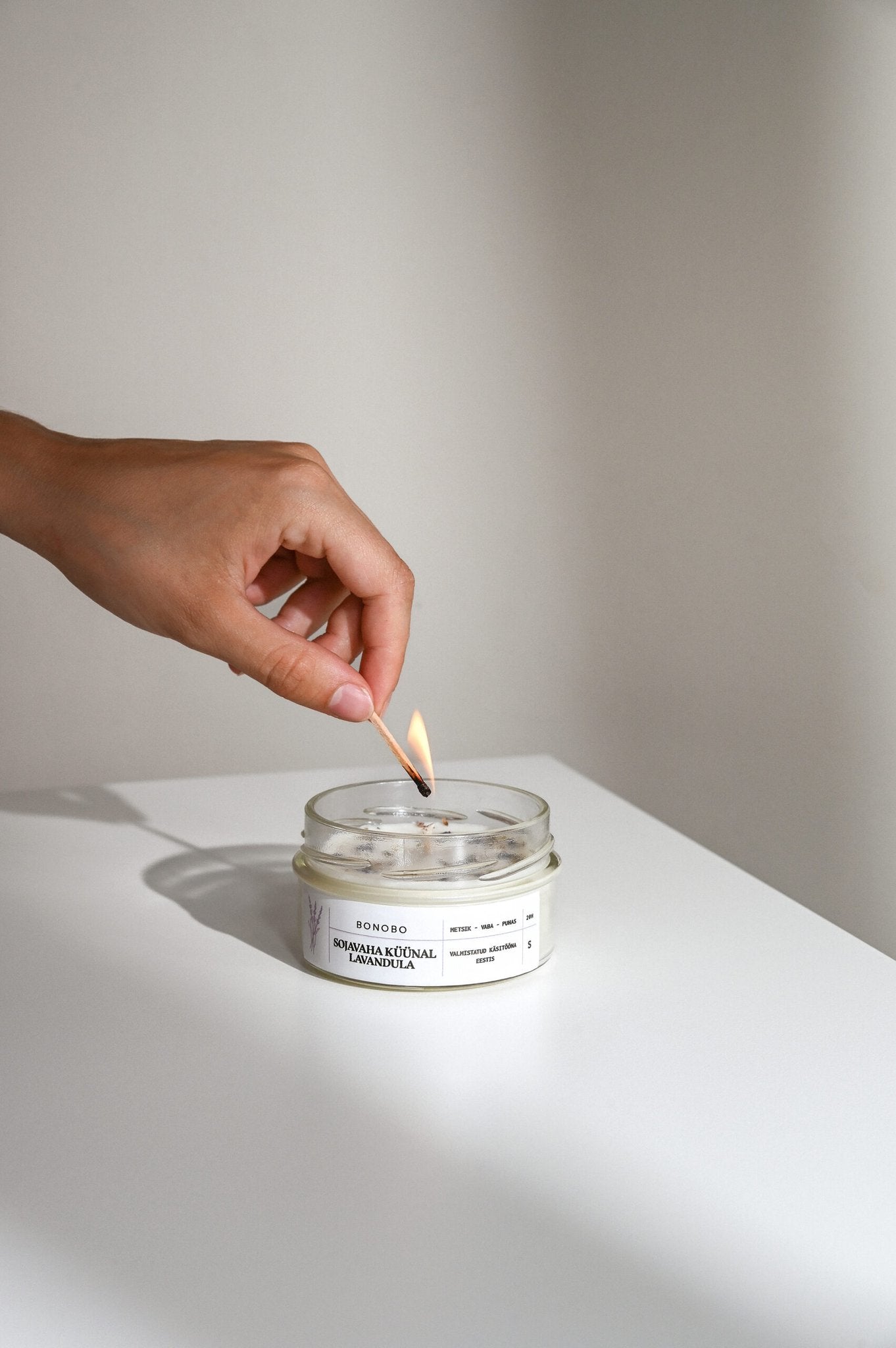 4. Hand lighting BONOBO Scented Candle Lavandula on a white surface