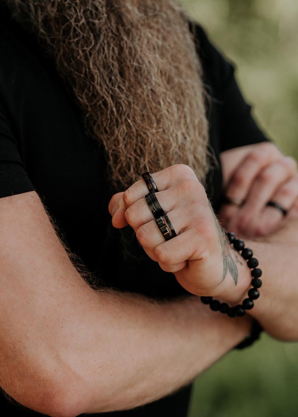 1. Man wearing black ceramic ring by Leomani with arms crossed outdoors