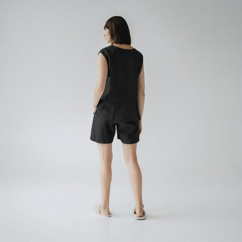 2. Woman shown from back wearing black linen pyjama set with sleeveless top and shorts, in a studio setting