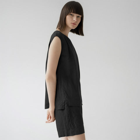 3. Side view of woman in black linen pyjama set with sleeveless top and shorts, in a studio setting