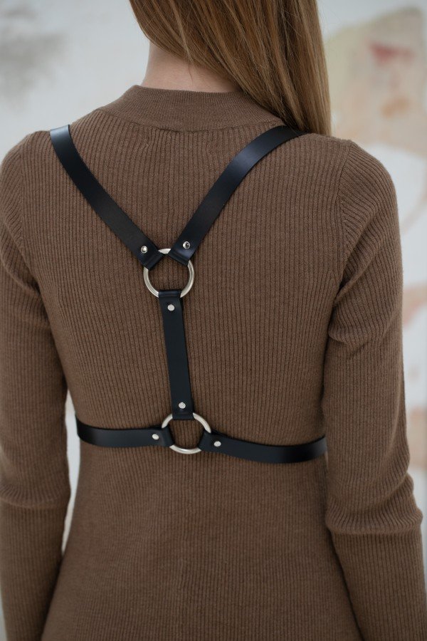 3. Back view of Body Harness Milla by PYKOK on a woman, showing leather straps and metal ring accents