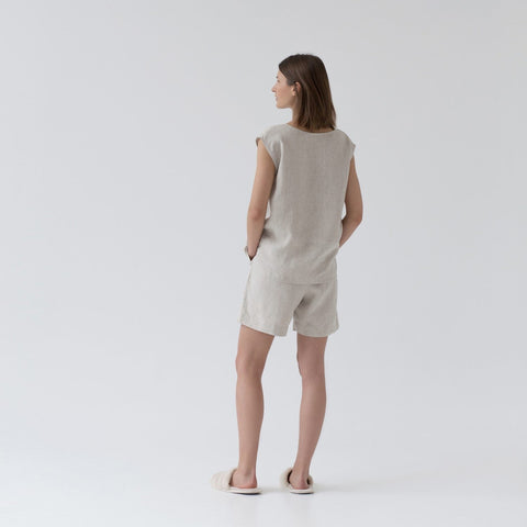 4. Woman wearing sleeveless beige linen pyjama set with relaxed fit, shown from back in a studio setting