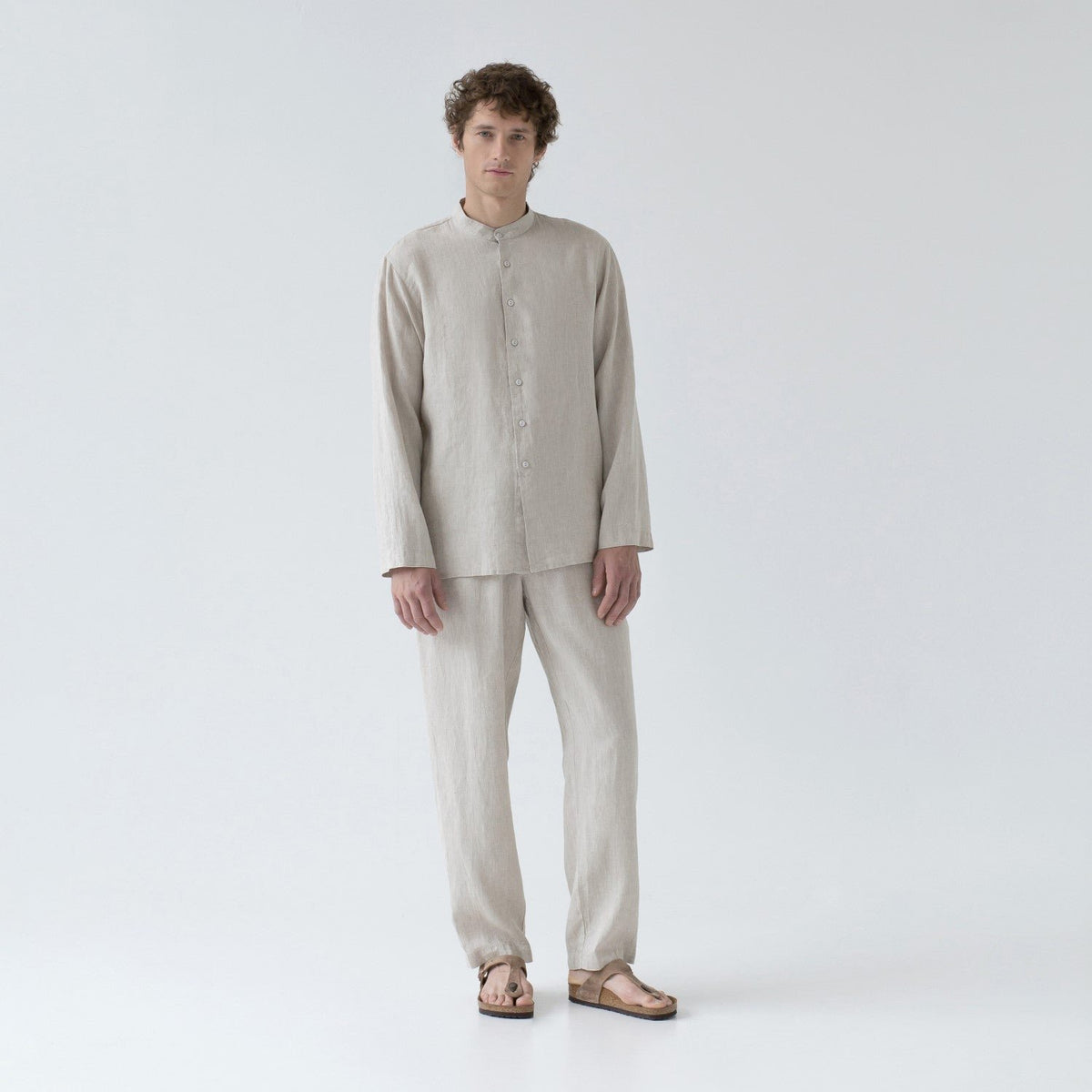 2. Man in beige linen loungewear set with buttoned top and relaxed trousers, standing in studio