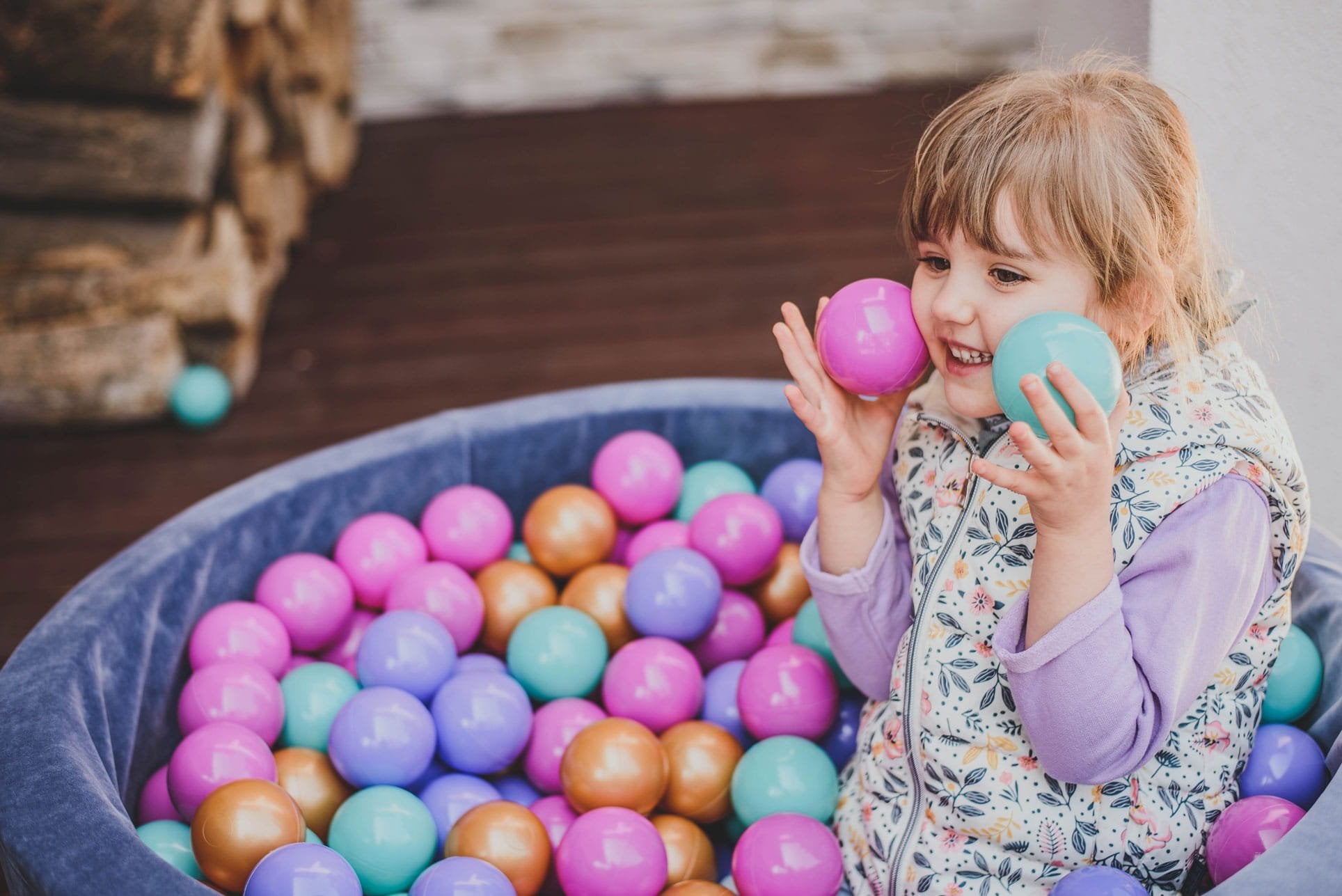 1. Young girl playing with colorful balls in a blue velvet MeowBaby ball pit outdoors
