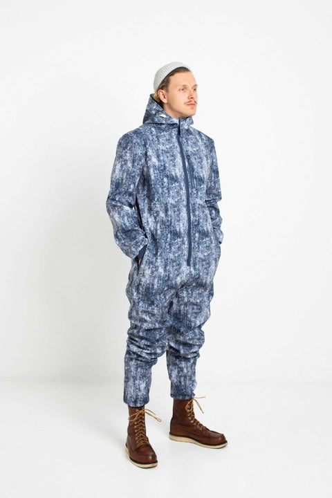 2. Man in Nuckö ERGO softshell overall with blue digital print, standing in studio with hands in pockets, looking to the side