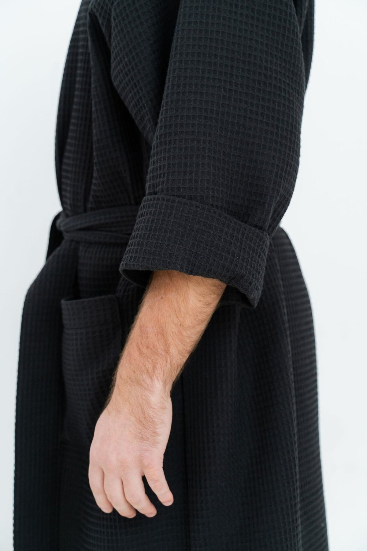 12. Close-up of black waffle robe showing sleeve and pocket detail