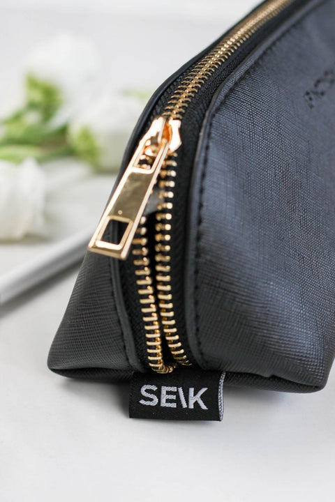 2. Close-up of SEIK black pencil case with gold zipper and brand tag, highlighting texture
