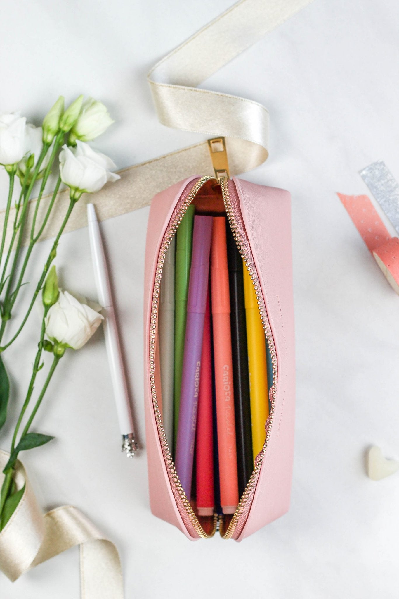 4. SEIK pink pencil case open with colorful pens inside, surrounded by flowers