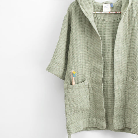 3. Close-up of sage green linen bathrobe showing pocket with toothbrush