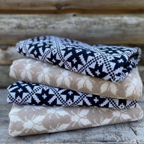 2. Stack of three terry sauna towels in beige and black with Hiiumaa County mitten pattern on wooden surface