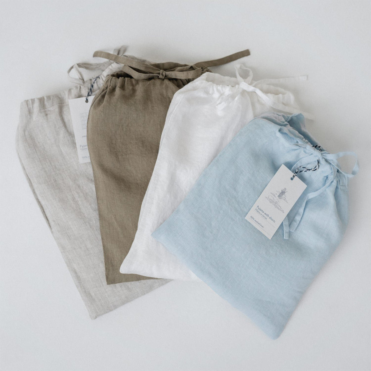5. Four linen bags in beige, brown, white, and blue with tags, laid flat