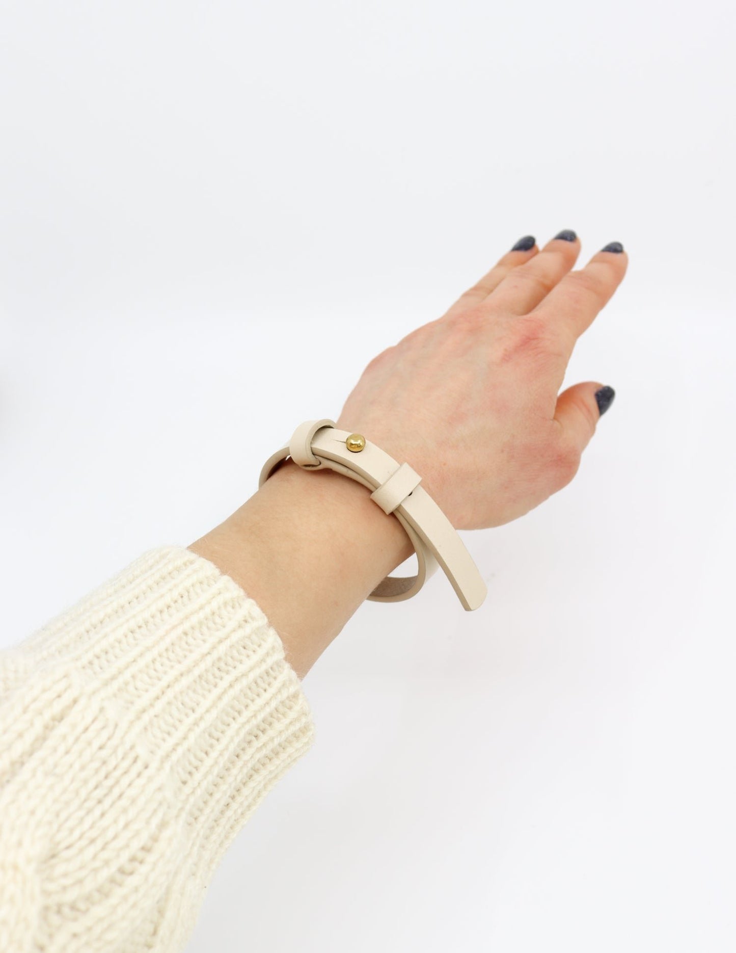 2. Women's ivory leather bracelet with brass fastener by Tairi Roosve, worn on wrist in studio setting