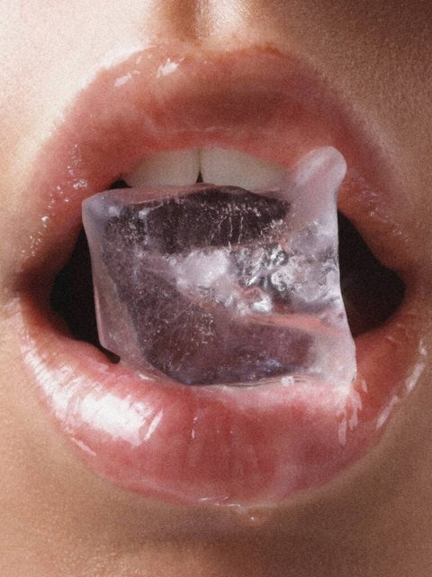 1. Close-up of glossy lips with ice cube, showcasing the hydrating effect of Magrada Organic Cosmetics Tinted Lip Balm Peach