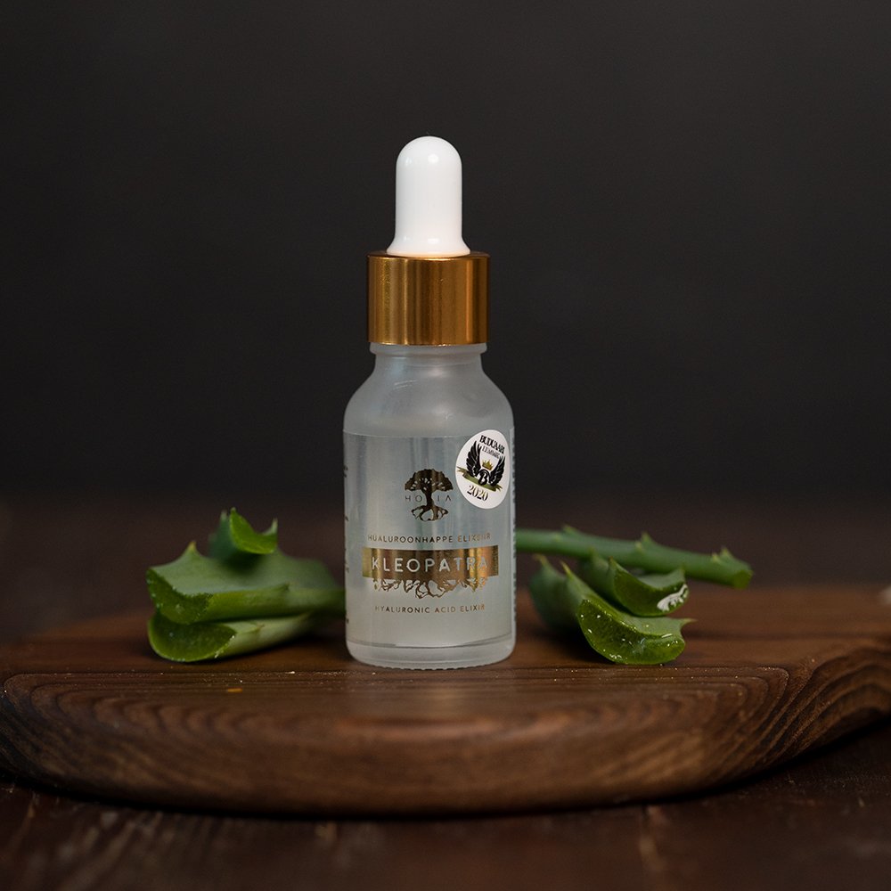 1. HOIA homespa Hyaluronic Acid Elixir Kleopatra bottle on wooden surface with aloe leaves, lifestyle setting