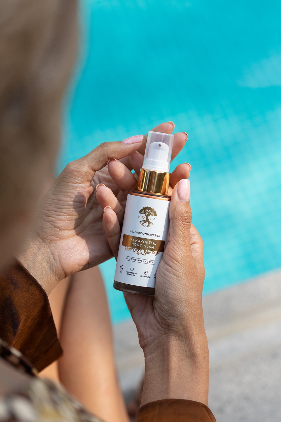 2. Woman applying HOIA homespa Body Cocktail Body Glam by the pool, highlighting product use