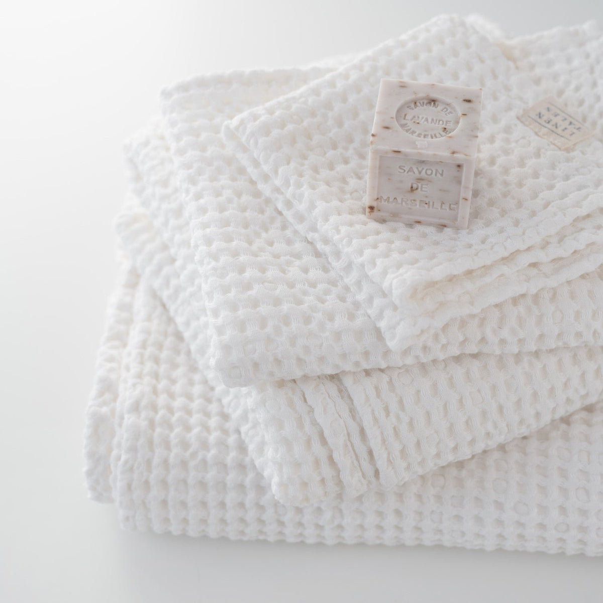 2. Stack of white honeycomb waffle towels with soap bars, highlighting texture and softness