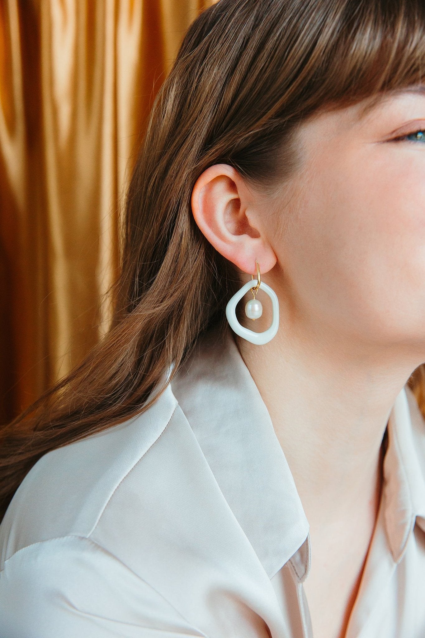 1. Woman wearing Rozenthal Arp Pearl and Porcelain Hoops in burgundy, showcasing elegant design
