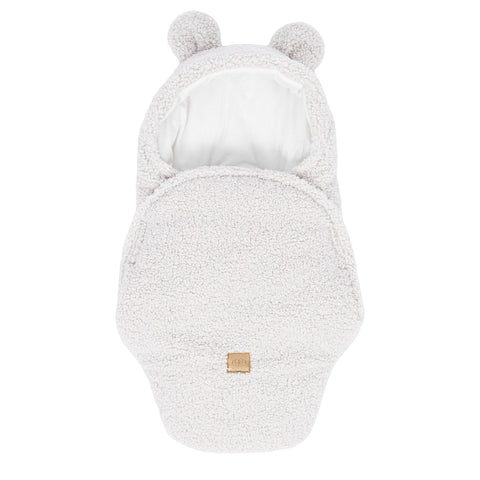 1. Off-white baby swaddle with bear ears made of boucle fabric, featuring a cotton inner layer and velcro closure, shown in a flat lay view