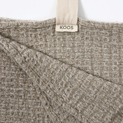 2. Close-up of grey textured linen towel with KOOSdisain label and cotton hanger