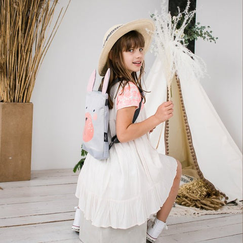1. Girl holding Muni Bunny kids backpack in outdoor setting, showcasing playful design