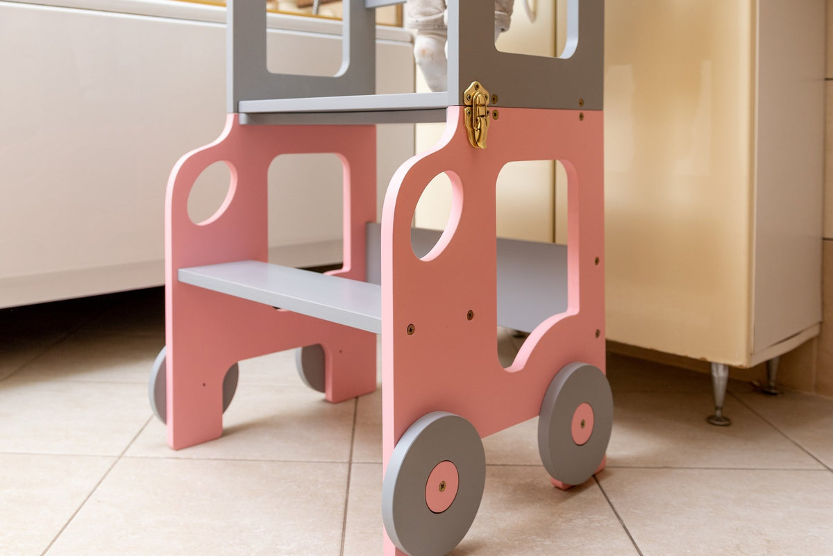 2. Pink and grey Montessori kitchen step stool with wheel design on tiled floor