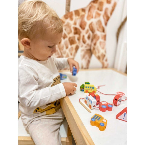 1. Toddler playing with colorful wooden threading blocks shaped like vehicles and road signs on a table