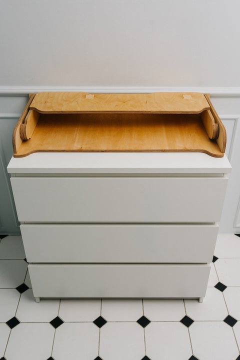 4. Birch plywood changing table top on white chest of drawers in a tiled room