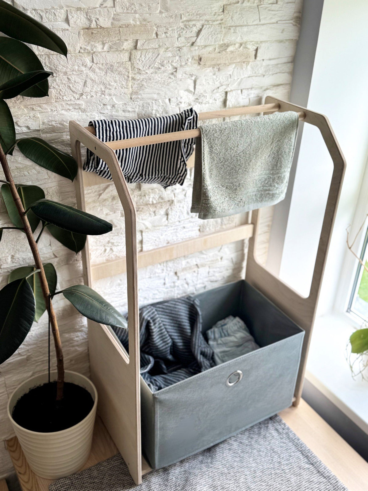 3. Wooden clothes drying rack with striped and grey towels, grey fabric basket in a bright room
