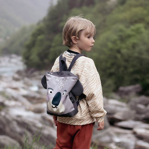 4. Child with Muni Koala backpack by river, showcasing outdoor adventure and adjustable straps