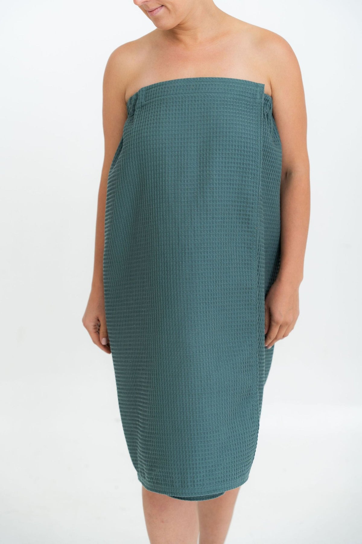 2. Woman wearing petrol cotton waffle sauna wrap in studio setting