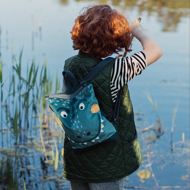 7. Flat lay of Muni dinosaur backpack with adventure accessories