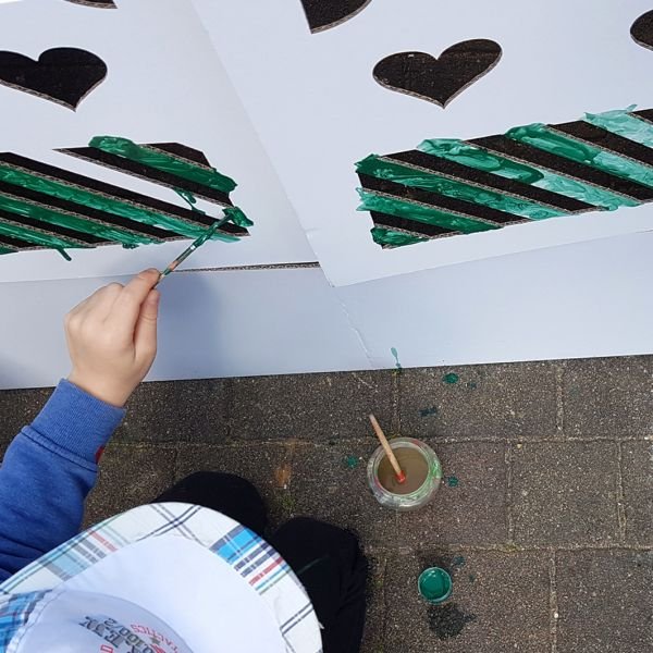 7. Child painting SEIK cardboard house with green paint, showing creative play