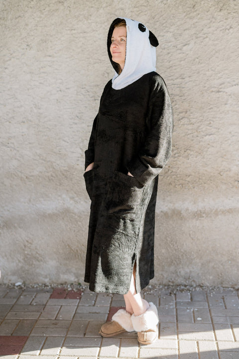 2. Unisex bamboo terry poncho by RÄTT with panda hood, worn by a woman, showcasing full length and side slits in lifestyle setting
