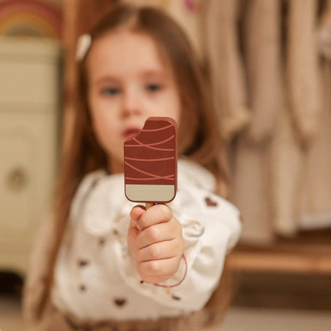 1. Child holding a wooden popsicle from the pastel ice cream cart playset